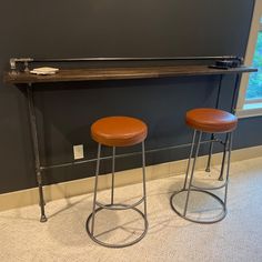 two brown stools sitting next to each other in front of a wall with a window