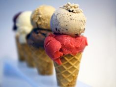 three scoops of ice cream with different toppings on them sitting in a row