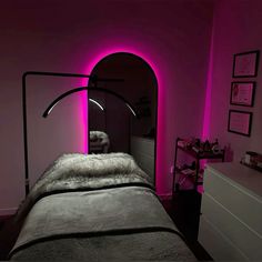 a room with a bed and pink lighting