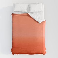 an orange and white ombreed comforter with two pillows on the bottom side