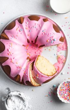 a cake with pink frosting and sprinkles on it sitting on a plate