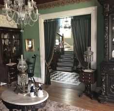 a living room filled with furniture and a chandelier hanging from the ceiling next to a doorway