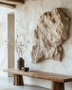 a table with vases sitting on top of it next to a stone wall mounted rock