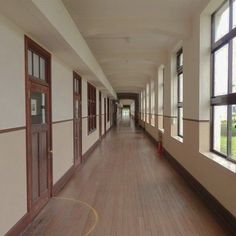 an empty hallway with wooden floors and windows