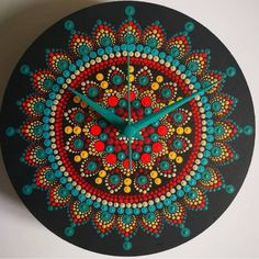 a clock that is on the wall and has colorful circles painted on it's face