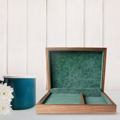 an open wooden box sitting on top of a table next to a vase with flowers