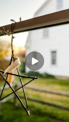 a star ornament hanging from a window sill in front of a white house