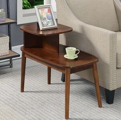 a small wooden table with a cup on it next to a chair and coffee mug