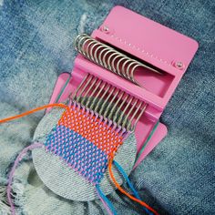 a pair of scissors and some colorful thread on a piece of denim with holes in it