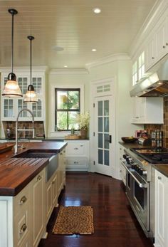 a large kitchen with white cabinets and wood counter tops, along with hardwood flooring