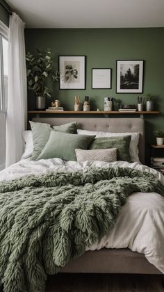 a bed with green blankets and pillows in front of two pictures on the wall above it