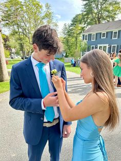 a young man in a blue suit and tie standing next to a woman wearing a blue dress