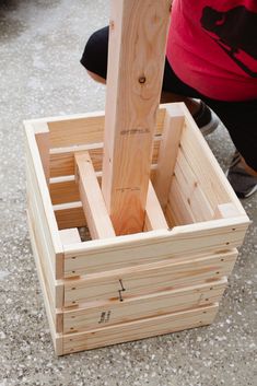 a wooden box that is sitting on the ground next to a persons leg and legs