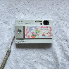 an old camera with some stickers on it's front and back side, sitting on a bed