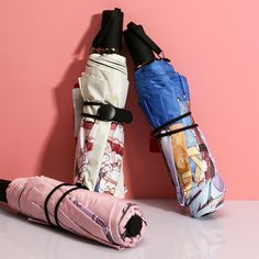 three umbrellas sitting next to each other on top of a white table and pink wall