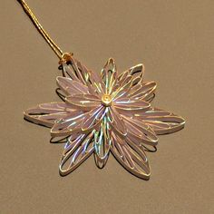 a necklace with a flower shaped pendant hanging from it's side on a table