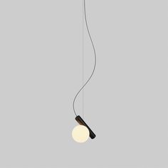 a black and white light hanging from a ceiling fixture on a gray wall with a round light bulb attached to it