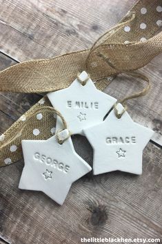 three white ceramic ornaments hanging from a burlock on a wooden table with the words grace and mile written on them