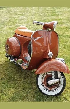 an orange scooter is parked in the grass