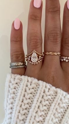 a woman's hand with three different rings on her fingers and one is wearing a sweater