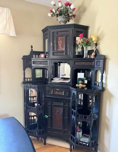 an ornate black cabinet with flowers on top