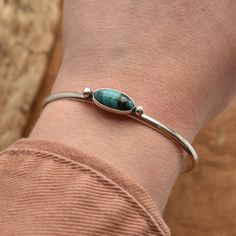 "*LBJ is moving this week to a new studio in Baltimore! There may be a slight delay in your order by a day or so while we get settled* In the shop this is called the Simple Cuff Bracelet - which is true. But when you're working with the wonderful stones we are -- like the gorgeous, AAA turquoise in this Turquoise Cuff Bracelet -- you don't need much embellishment besides the stone. Here we've used a low-dome half-round wire and two sterling silver bead embellishments to flank this 7X15mm Turquoi Silver Turquoise Jewelry Cuff Bracelets, Turquoise Cuff Jewelry For Gifts, Turquoise Metal Bangle Cuff Bracelet, Native Accessories, Simple Cuff Bracelet, Real Turquoise Jewelry, Southwestern Turquoise Sterling Silver Cuff Bracelet, Turquoise Bangle, Unique Nickel-free Turquoise Cuff Bracelet