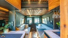 an interior view of a tiny home with wood paneling and white couches, built into the ceiling