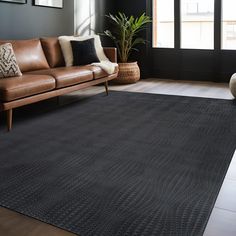 a living room with a brown leather couch and black rug on top of the floor