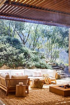 an outdoor living area with wood furniture and trees in the background