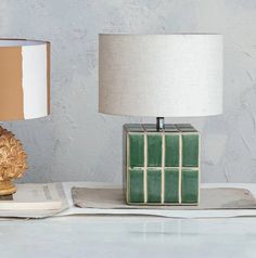 a table lamp sitting on top of a book next to a green cube shaped lamp