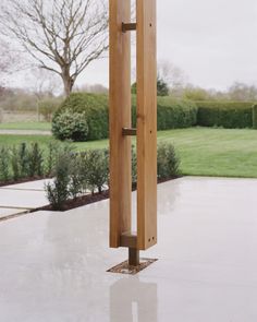 a tall wooden pole sitting in the middle of a garden next to a lush green field