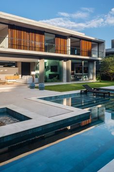 a large house with a pool in front of it and an outdoor dining area on the other side