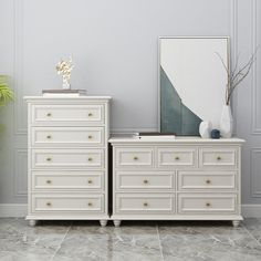 two white dressers in a room with a plant and mirror on the wall behind them