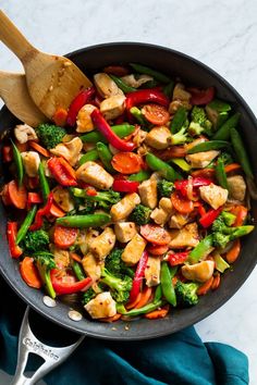 a skillet filled with chicken, broccoli and peppers