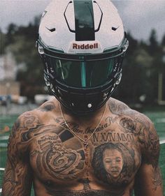 a shirtless man with tattoos and a football helmet