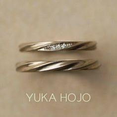 two gold rings with diamonds on them sitting next to the words yuka hojo