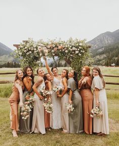 a group of women standing next to each other in front of a lush green field