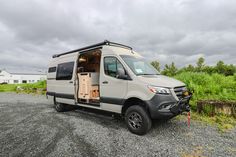 an rv parked on the side of a gravel road with its door open and windows opened