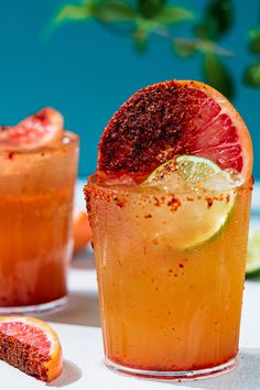 two glasses filled with blood orange margaritas and garnished with lime