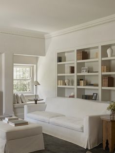 a living room filled with white furniture and bookshelves