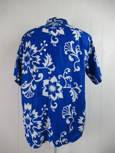 "Vintage 1960s blue and white cotton Hawaiian shirt. Has a matching pattern chest pocket, brass button front, top loop collar button and straight cut hem. Label reads: CREATED IN HAWAII FOR DIAMOND HEAD SPORTSWEAR. Size large. Measurements are: 45\" around the chest 45\" around the waist 18\" shoulder seam to shoulder seam 30\" overall length In very good condition." Retro Blue Button-up Hawaiian Shirt, Blue Retro Hawaiian Button-up Shirt, Blue Cotton Hawaiian Shirt With Hibiscus Print, Blue Hawaiian Shirt With Floral Print And Camp Collar, Blue Printed Button-up Hawaiian Shirt, Blue Printed Hawaiian Button-up Shirt, Blue Floral Print Button-up Hawaiian Shirt, Blue Floral Print Hawaiian Button-up Shirt, Blue Retro Button-up Camp Shirt