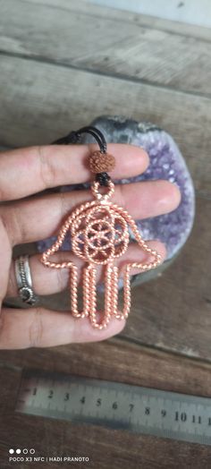 a person is holding a small hamsa pendant