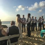 a group of people standing on top of a sandy beach next to the ocean with chairs