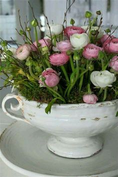 a white bowl filled with flowers on top of a table