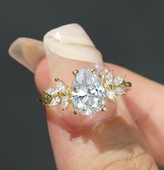 a close up of a person's hand holding an engagement ring