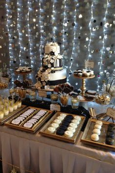 a table topped with cakes and desserts under a wall covered in confetti