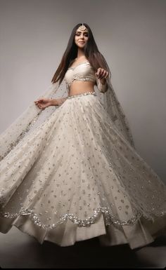 a woman in a white and gold lehenga with long hair wearing a veil