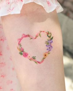 a heart shaped tattoo with flowers painted on it