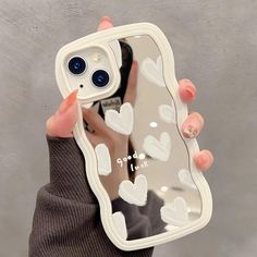 a person holding up a phone case with hearts on it