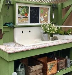 an outdoor kitchen with green walls and white sink in the center is filled with flowers